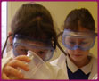 Erin concentrates hard as she pours vinegar but just watch the yellow balloon on the desk girls